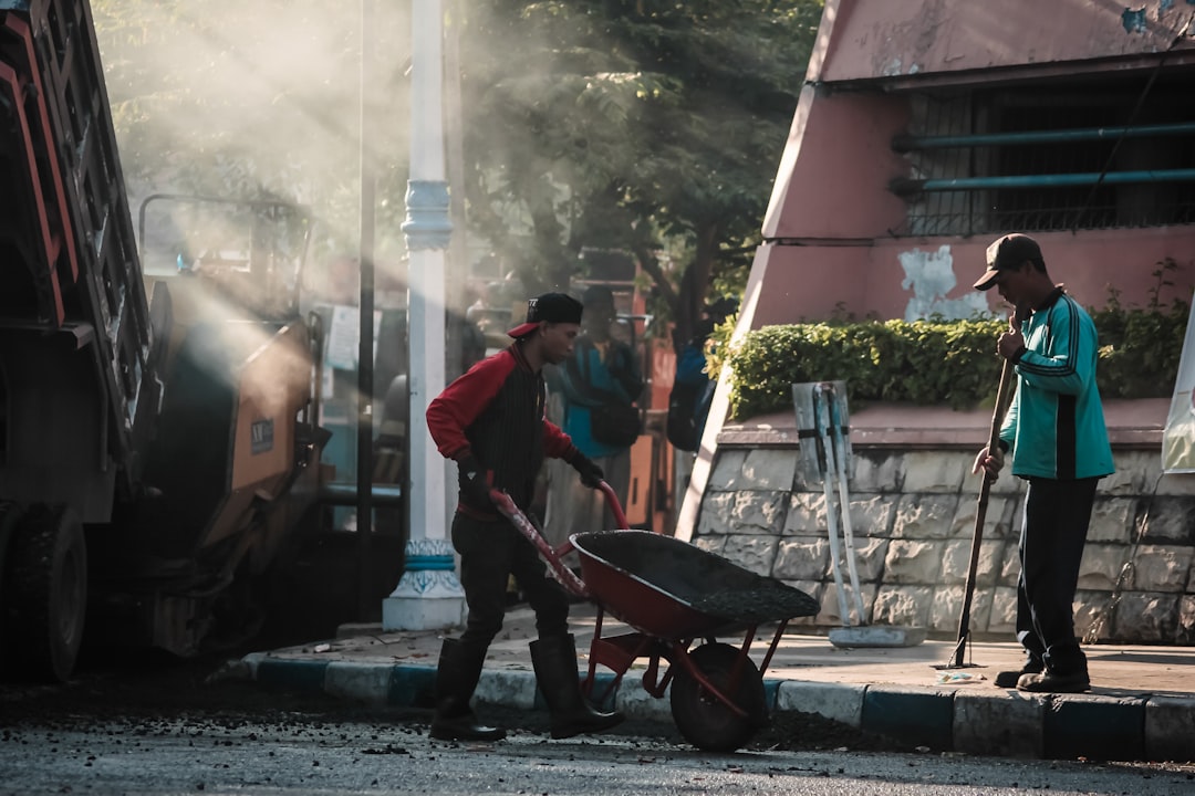 person-in-black-holding-wheelbarrow-in-front-of-man-in-teal-top-during-daytime-5roqhlhkvgw