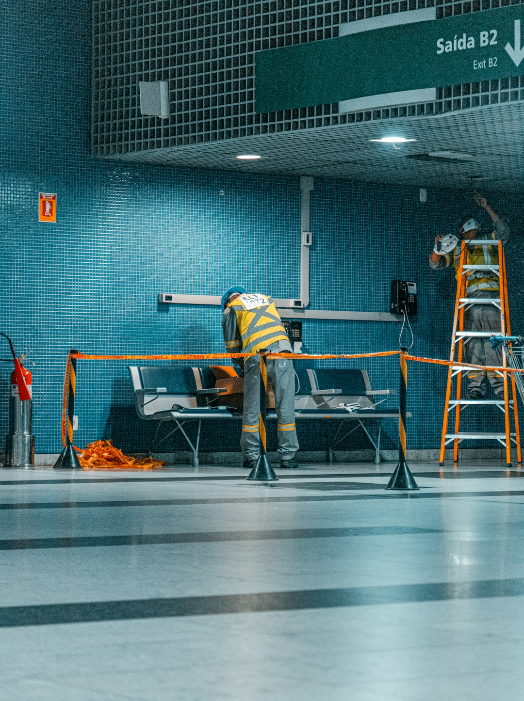 man-in-yellow-and-black-jacket-and-black-pants-standing-near-gray-metal-table-izfenxlciiw